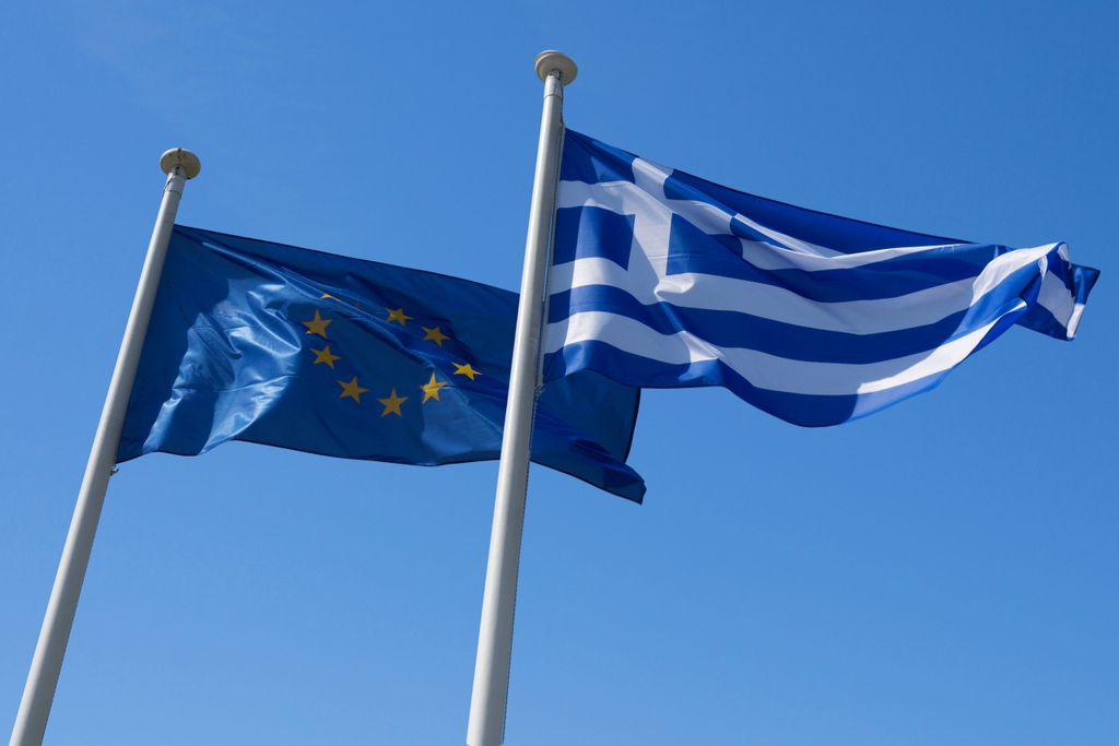 A Greek and EU flag side by side.