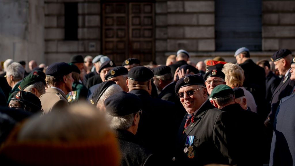 A crowd of older people in military dress gather in front of a building.